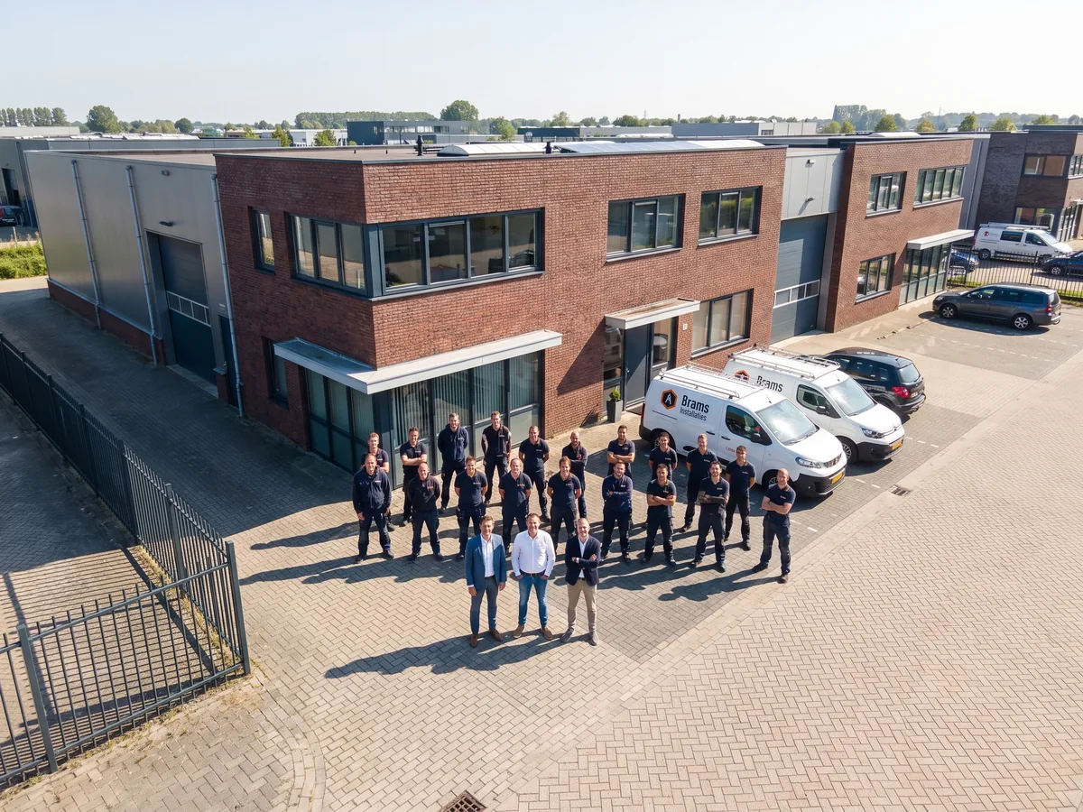 brams-installaties-teamfoto-bedrijfspand-busjes-op-de-foto-is-een-groep-medewerkers-te brams installaties teamfoto bedrijfspand busjes op de foto is een groep medewerkers te